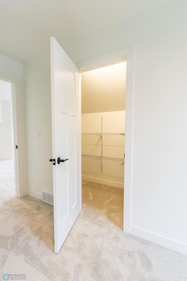 hallway with visible vents, baseboards, and carpet flooring