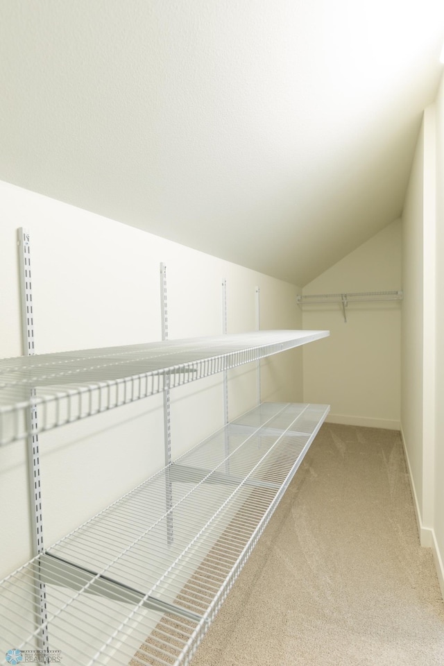 walk in closet with carpet flooring and vaulted ceiling