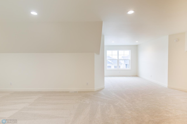 spare room featuring light colored carpet, recessed lighting, and baseboards