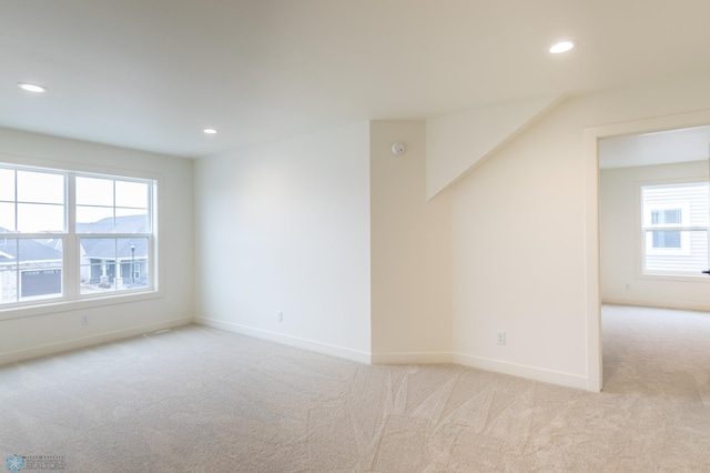 spare room with light colored carpet, recessed lighting, and baseboards