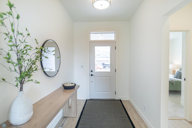 doorway with light wood-type flooring and baseboards