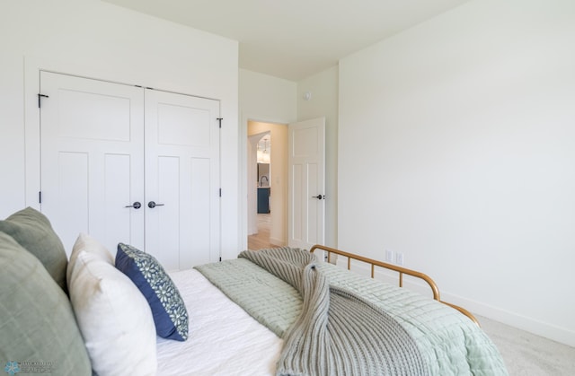bedroom featuring light carpet, baseboards, and a closet