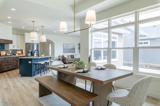 dining room with healthy amount of natural light, arched walkways, light wood-type flooring, and recessed lighting