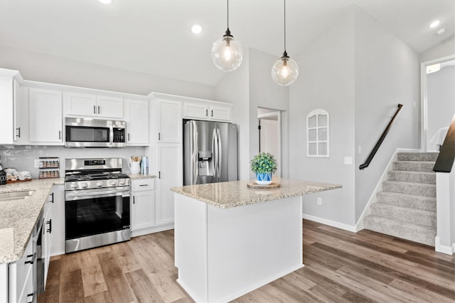 kitchen featuring hanging light fixtures, appliances with stainless steel finishes, white cabinetry, and light wood-style floors