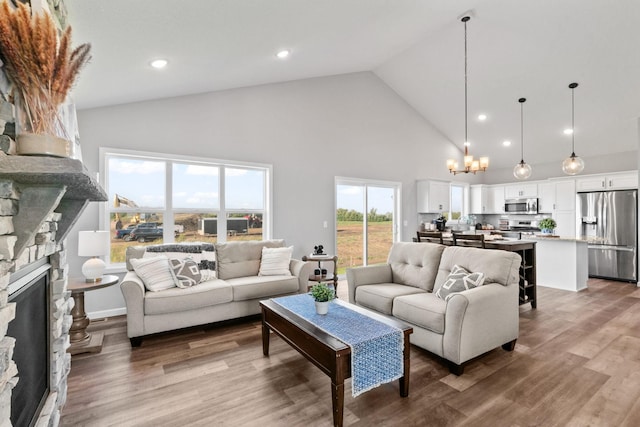 living area featuring a chandelier, high vaulted ceiling, recessed lighting, a fireplace, and wood finished floors