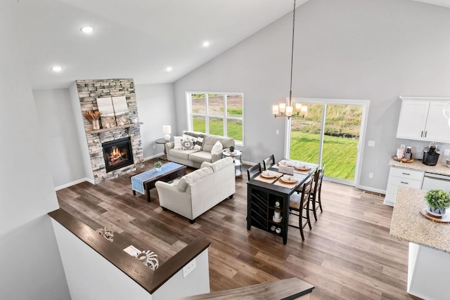 living room with a chandelier, high vaulted ceiling, recessed lighting, a fireplace, and wood finished floors