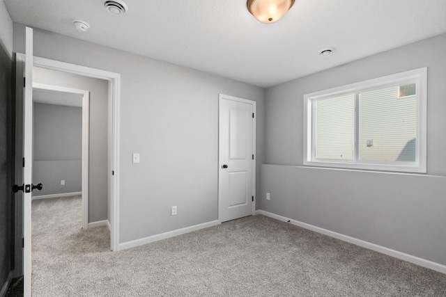 unfurnished bedroom with carpet, visible vents, and baseboards