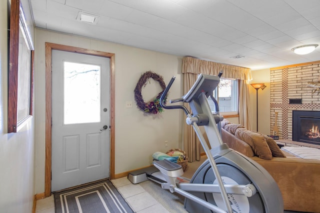 workout area with light tile patterned floors, a fireplace, and baseboards