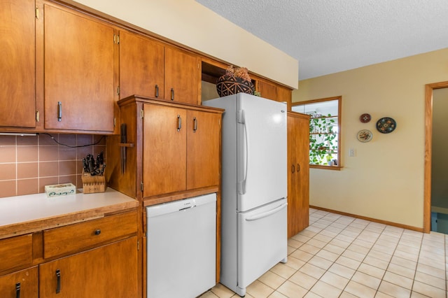 kitchen featuring white appliances, light tile patterned floors, brown cabinets, light countertops, and tasteful backsplash