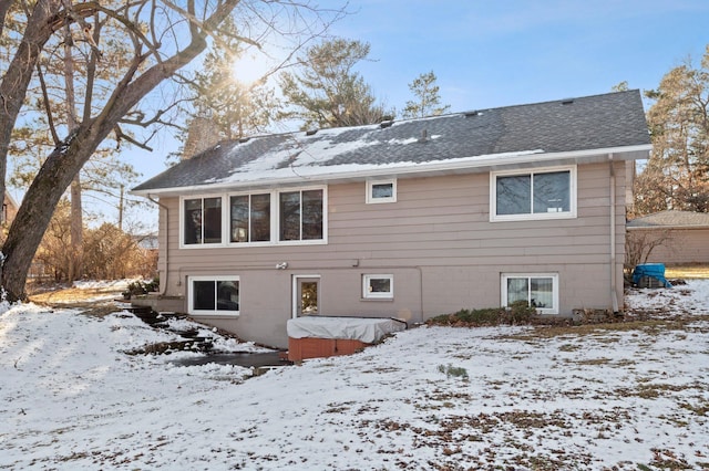 snow covered back of property with a chimney and roof with shingles