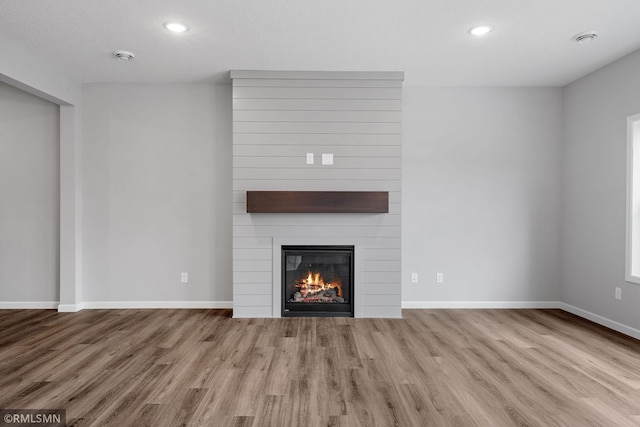 unfurnished living room with a fireplace, baseboards, and wood finished floors