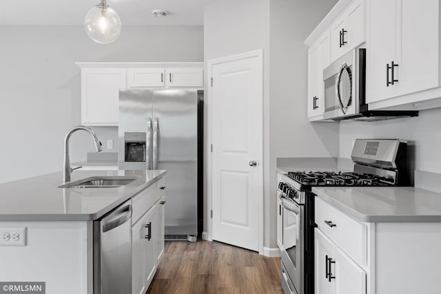 kitchen with white cabinets, stainless steel appliances, a sink, and wood finished floors