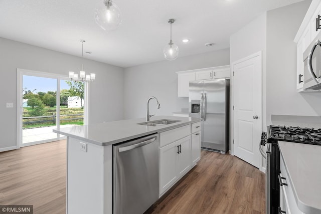 kitchen featuring a center island with sink, white cabinets, appliances with stainless steel finishes, light wood-style floors, and a sink