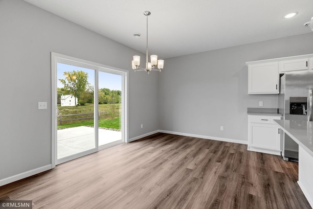 unfurnished dining area featuring a notable chandelier, baseboards, and wood finished floors