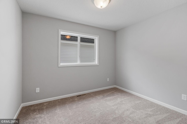 carpeted empty room with visible vents and baseboards