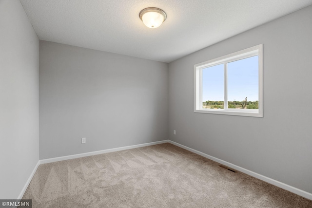 carpeted spare room with baseboards, visible vents, and a textured ceiling