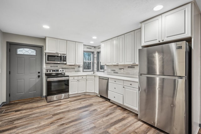 kitchen featuring appliances with stainless steel finishes, light countertops, light wood-style floors, and white cabinetry