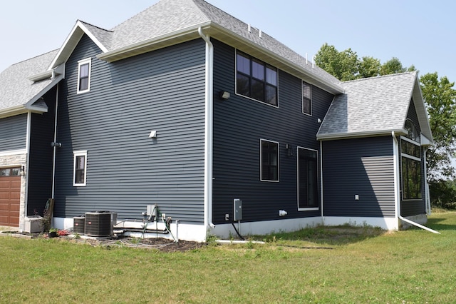 12424 126th Ave NE, Thief River Falls, MN 56701 - back of house featuring a lawn, cooling unit, a shingled roof, and a garage