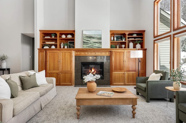 living area featuring light carpet, a tiled fireplace, and a high ceiling