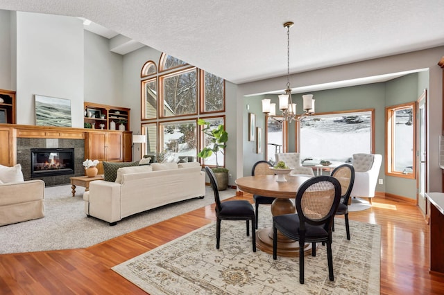 dining space featuring a chandelier, a high end fireplace, a textured ceiling, and wood finished floors