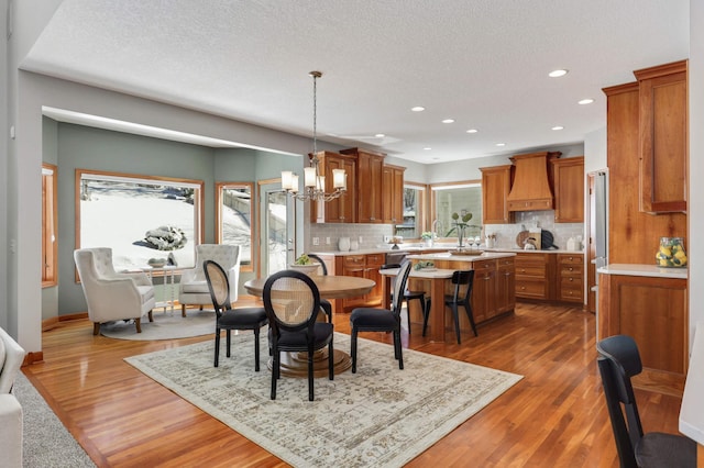 dining area with recessed lighting, an inviting chandelier, a textured ceiling, wood finished floors, and baseboards