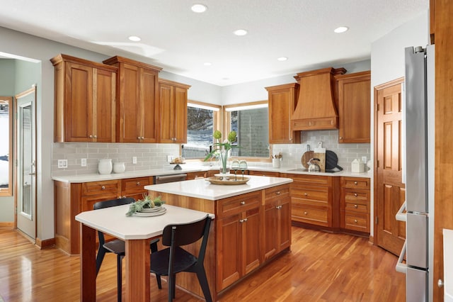 kitchen with brown cabinets, custom exhaust hood, and stainless steel appliances