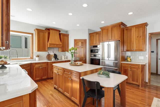 kitchen with premium range hood, appliances with stainless steel finishes, and brown cabinetry