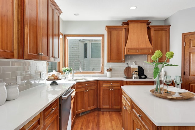 kitchen featuring brown cabinetry, light countertops, light wood-style floors, premium range hood, and a sink