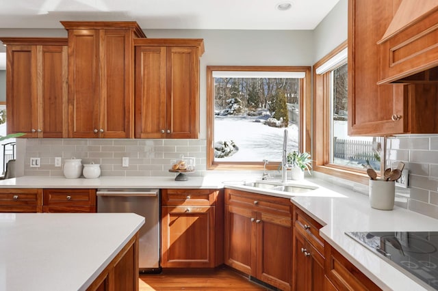 kitchen featuring a wealth of natural light, light countertops, stainless steel dishwasher, and black electric cooktop