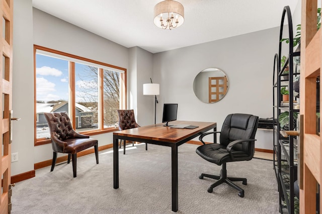 carpeted home office featuring a chandelier and baseboards