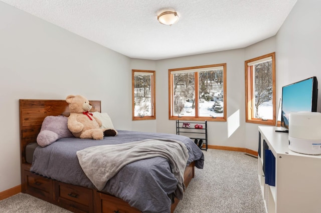 bedroom with light carpet, baseboards, and a textured ceiling