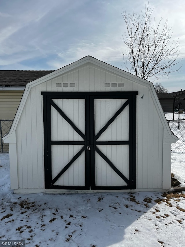 snow covered structure with an outbuilding and a storage shed