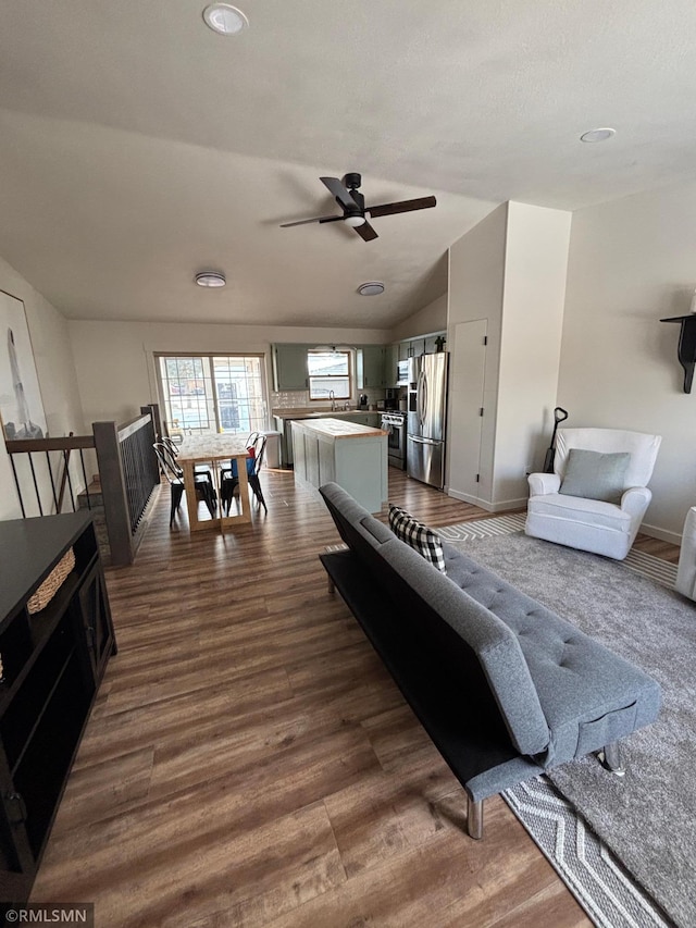 living area with lofted ceiling, dark wood finished floors, and baseboards