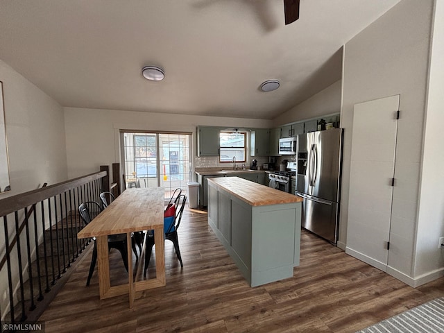 kitchen featuring butcher block counters, appliances with stainless steel finishes, dark wood-style flooring, vaulted ceiling, and a sink