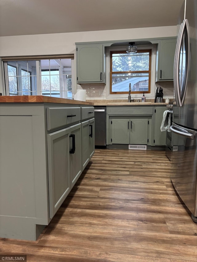 kitchen with wood finished floors, a sink, freestanding refrigerator, and a healthy amount of sunlight