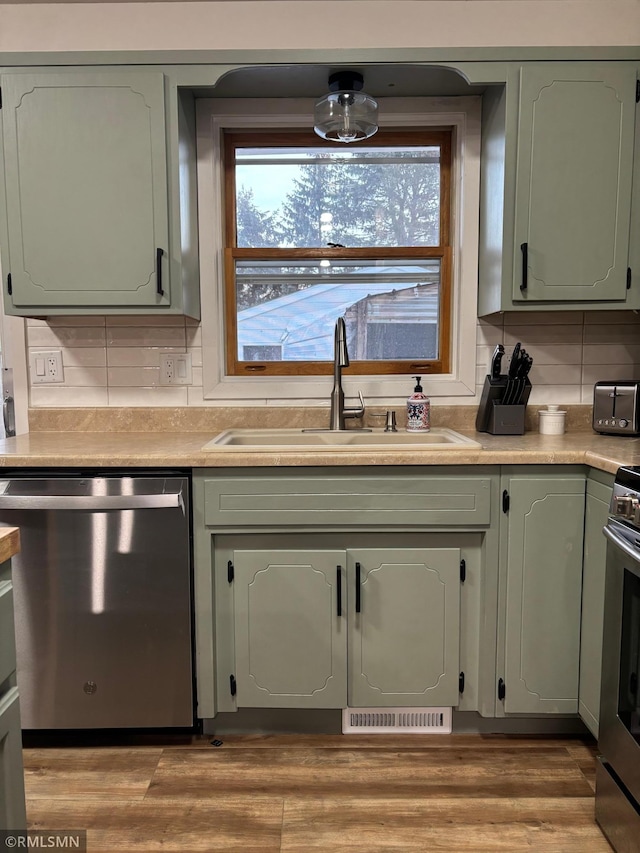 kitchen featuring green cabinets, appliances with stainless steel finishes, and a sink