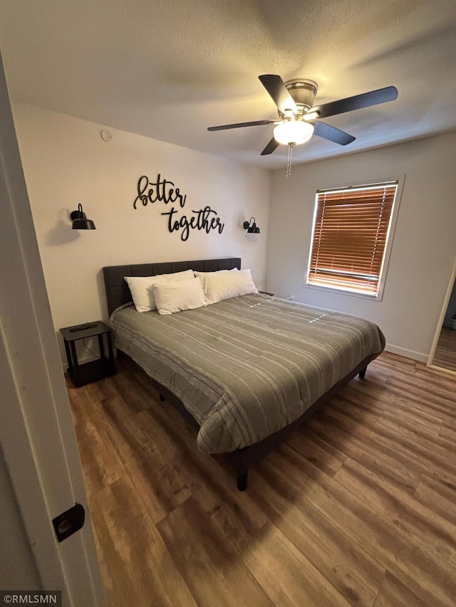 bedroom with a textured ceiling, wood finished floors, a ceiling fan, and baseboards