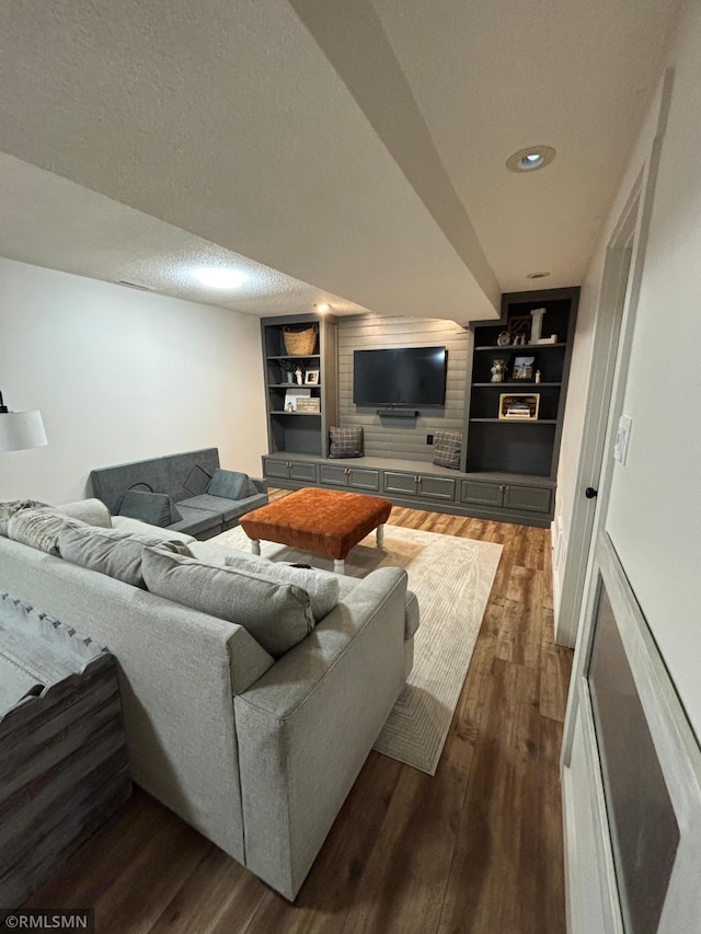 living area featuring built in shelves, a textured ceiling, and wood finished floors