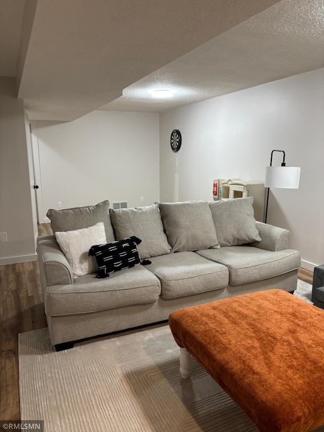 living area with a textured ceiling, wood finished floors, and baseboards