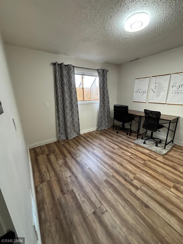 office space featuring a textured ceiling, wood finished floors, and baseboards