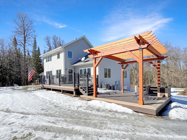 snow covered rear of property featuring central AC, a pergola, and a wooden deck