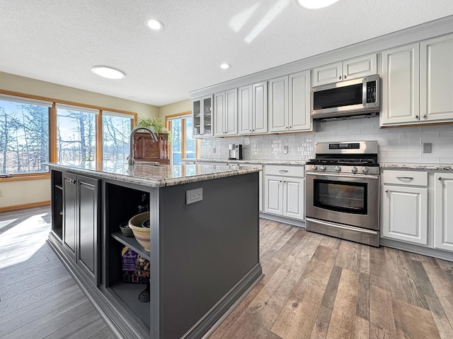 kitchen with stainless steel appliances, light wood-type flooring, decorative backsplash, and a center island