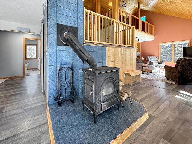 living room with high vaulted ceiling, wood ceiling, a wood stove, and wood finished floors