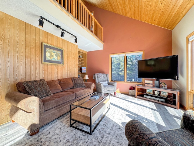 living room with wood walls, wood ceiling, high vaulted ceiling, and track lighting