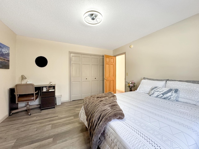 bedroom with a textured ceiling, a closet, light wood-type flooring, and baseboards