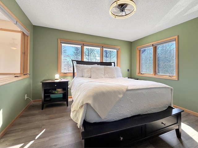 bedroom featuring a textured ceiling, wood finished floors, and baseboards