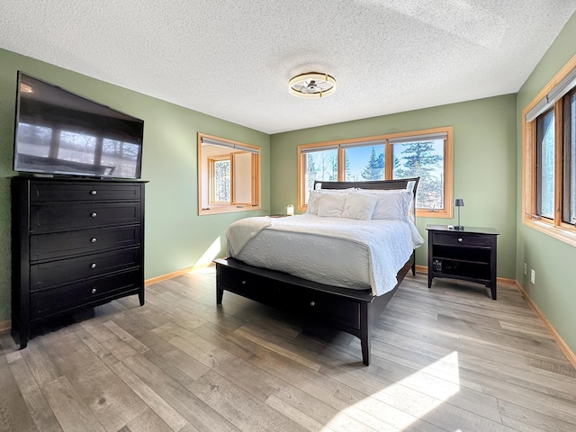 bedroom with baseboards, multiple windows, and light wood-style floors