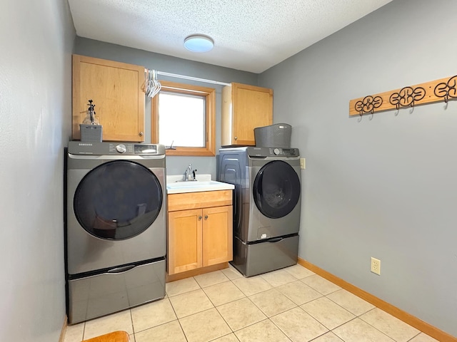 laundry room with cabinet space, baseboards, a textured ceiling, separate washer and dryer, and a sink