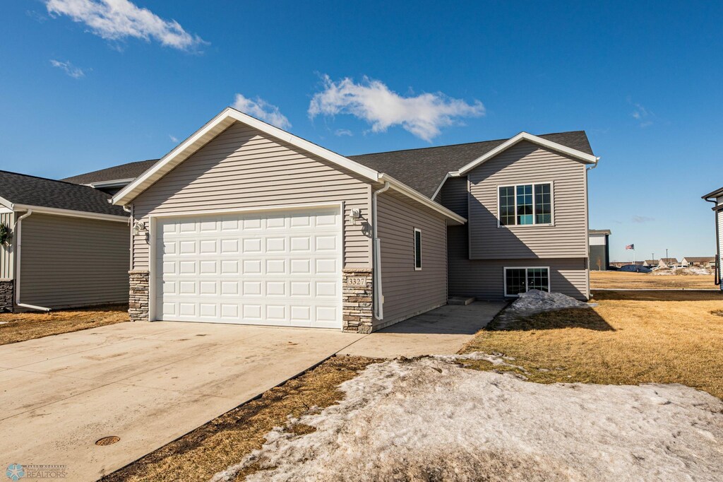 view of front of property with a garage, stone siding, and concrete driveway