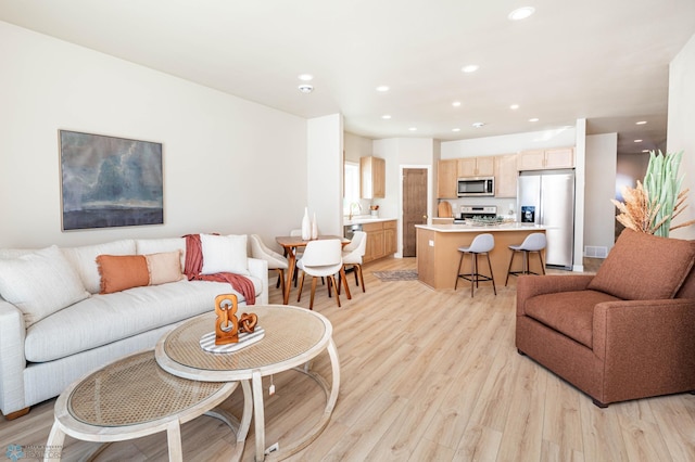 living area with light wood-type flooring, visible vents, and recessed lighting